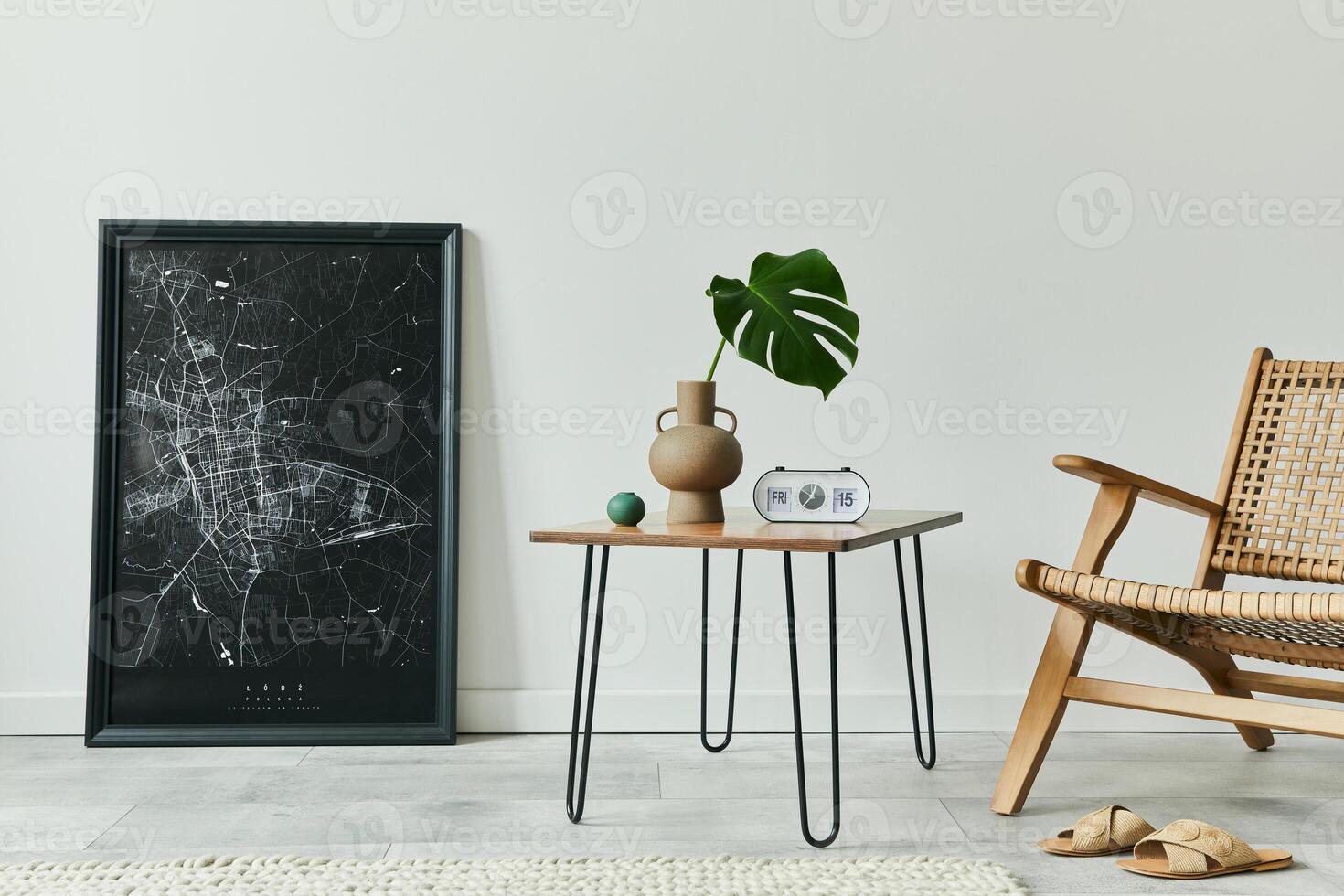Minimalist concept of living room interior with rattan armchair, walnut coffee table, tropical leaf in vase, clock, black mock up poster map and personal accessories in stylish home decor. Template. photo