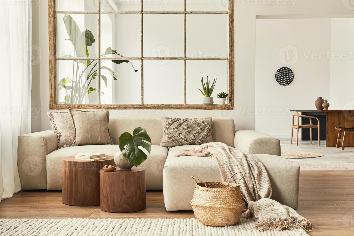 Modern interior of open space with design modular sofa, furniture, wooden coffee tables, plaid, pillows, tropical plants and elegant personal accessories in stylish home decor. Neutral living room. photo