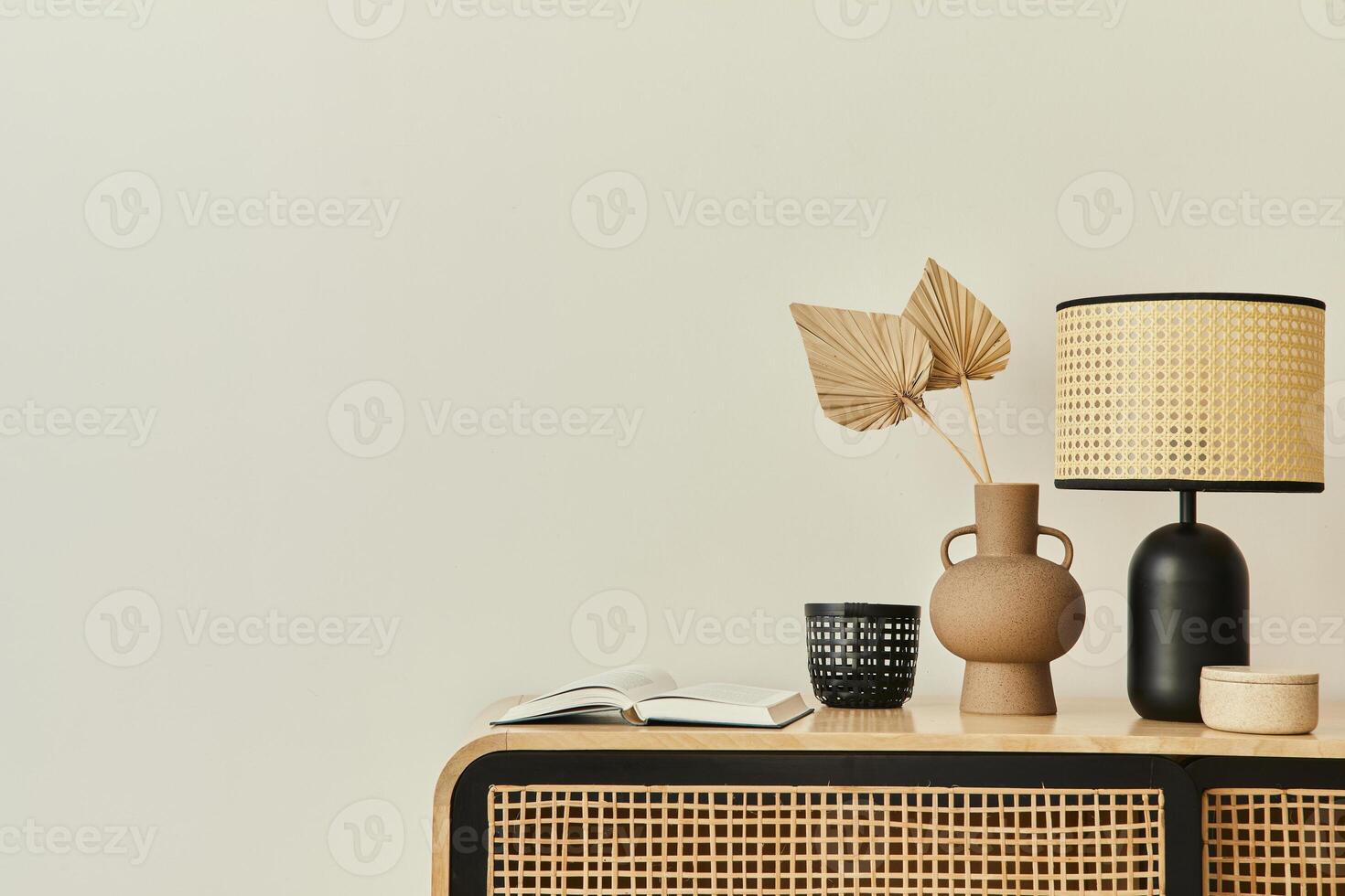 Modern scandinavian home interior with design wooden commode, dried leaf in vase, books, table lamp and personal accessories in stylish home decor. Template. Copy space. White walls. photo
