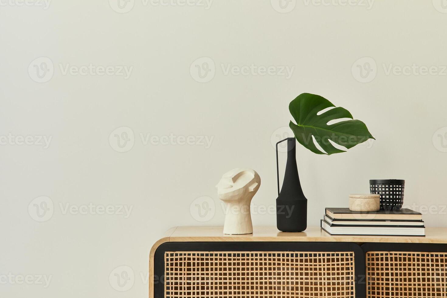 Modern scandinavian home interior with design wooden commode, tropical leaf in vase, books and personal accessories in stylish home decor. Template. Copy space. White walls. photo