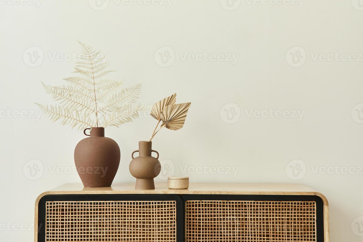 Modern scandinavian home interior with design wooden commode, dried leafs in ceramic vases and personal accessories in stylish home decor. Template. Copy space. White walls. photo