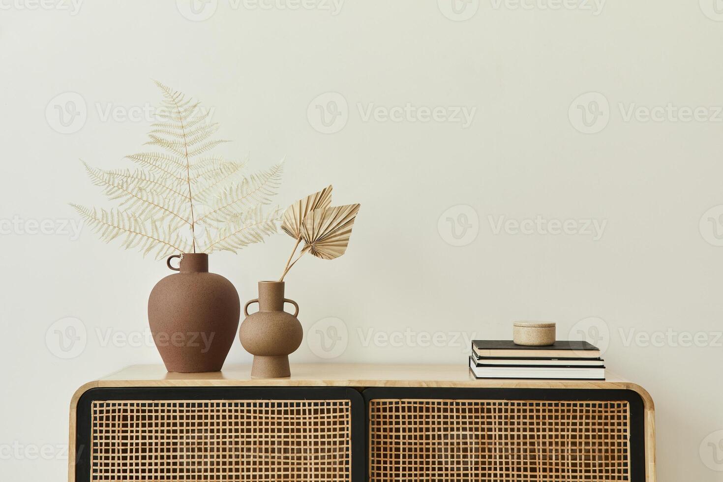 Modern scandinavian home interior with design wooden commode, dried leafs in ceramic vases and personal accessories in stylish home decor. Template. Copy space. White walls. photo