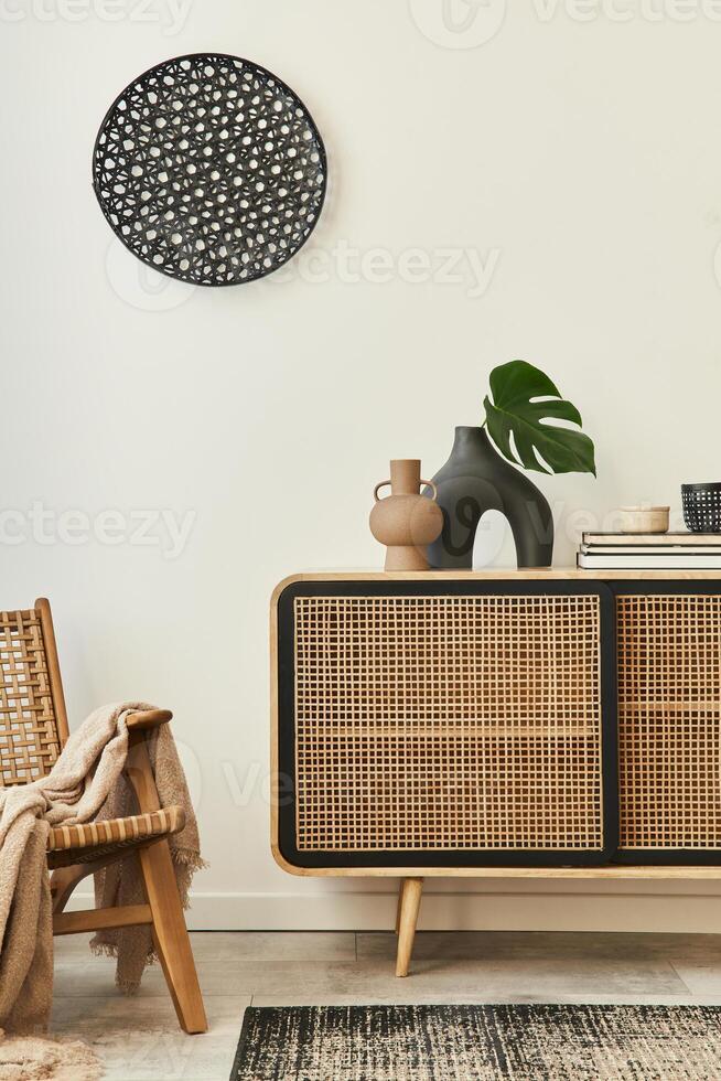 Stylish scandinavian living room interior of modern apartment with wooden commode, design armchair, carpet, leaf in vase, book and personal accessories in unique home decor. Template. photo