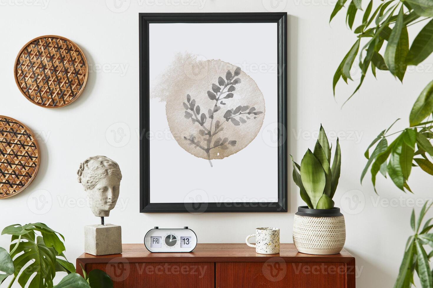 Retro modern compositon of living room interior with design teak commode, black mock up poster frame, clock, plant, decoration, white wall and personal accessories. Template. photo