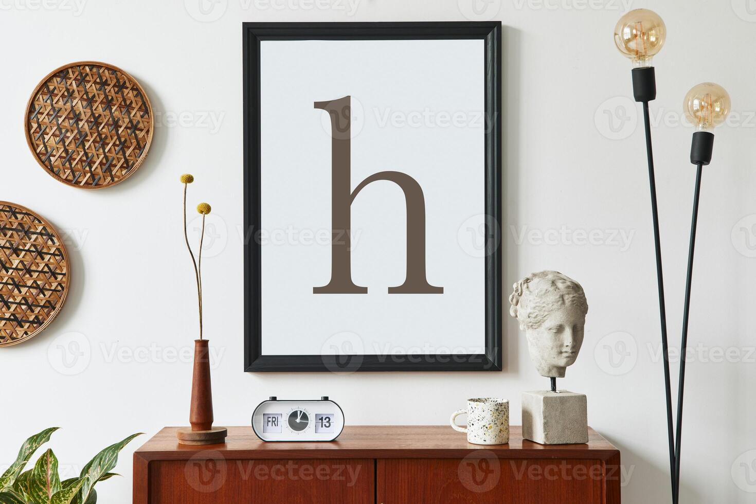 Retro modern compositon of living room interior with design teak commode, black mock up poster frame, clock, dried flower, decoration, white wall and personal accessories. Template. photo