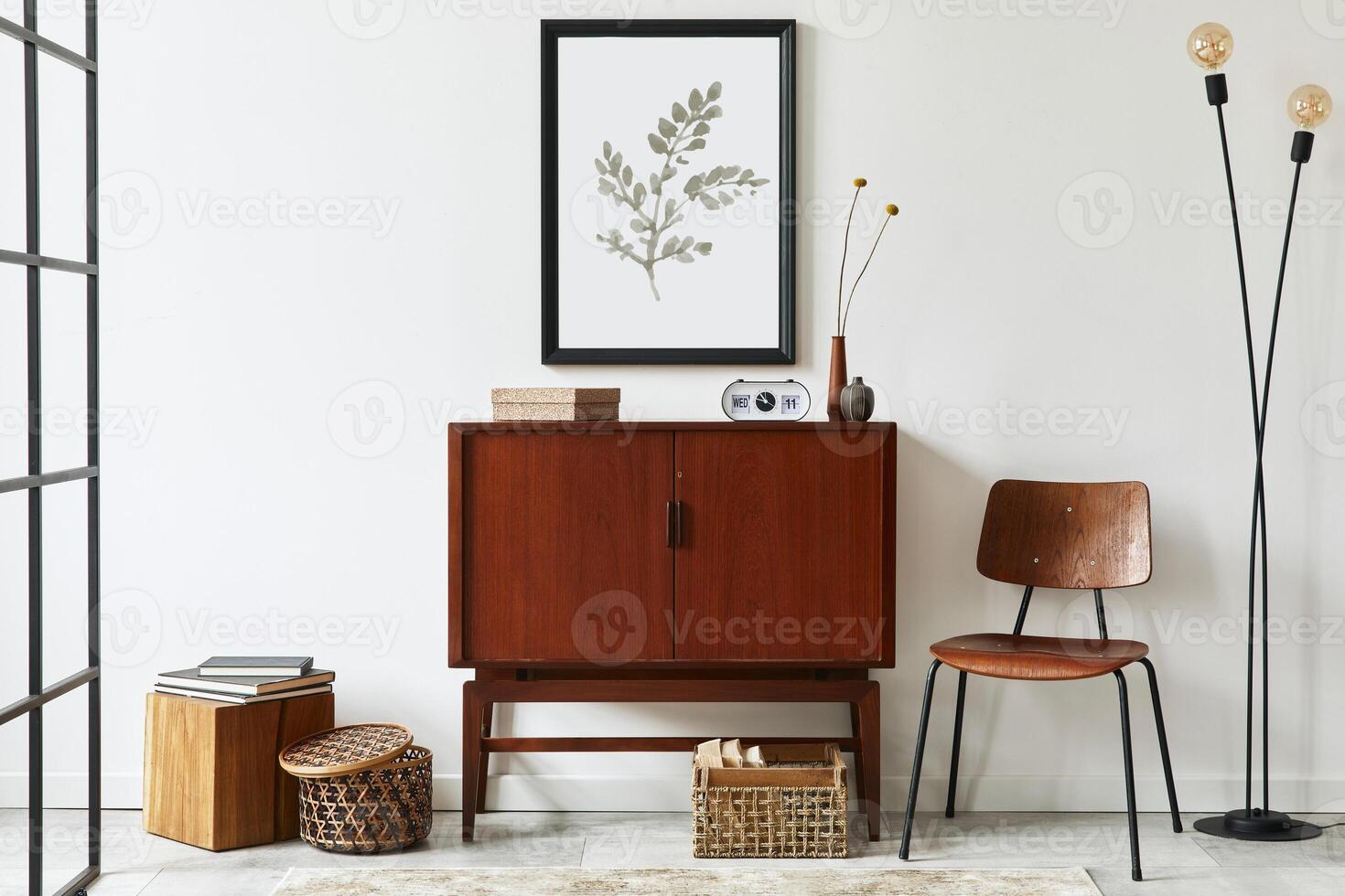 Modern retro concept of living room interior with design teak commode, black mock up poster frame, clock, chair, decoration, wooden cube, book, lamp, white wall and personal accessories. Template. photo