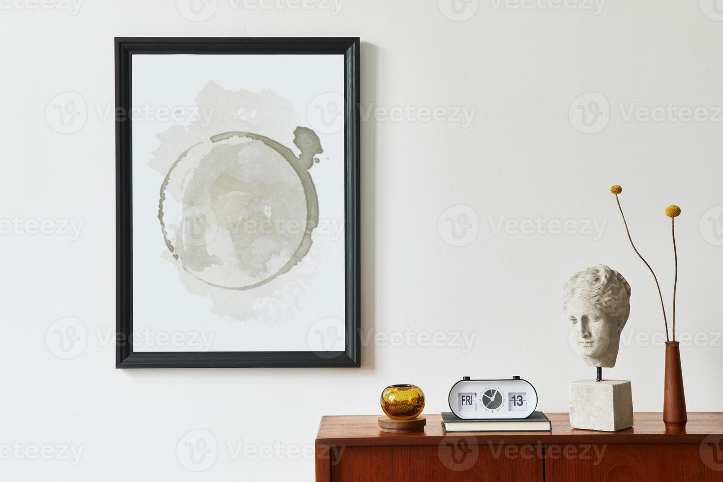 Retro modern compositon of living room interior with design teak commode, black mock up poster frame, clock, dried flower, decoration, white wall and personal accessories. Template. photo