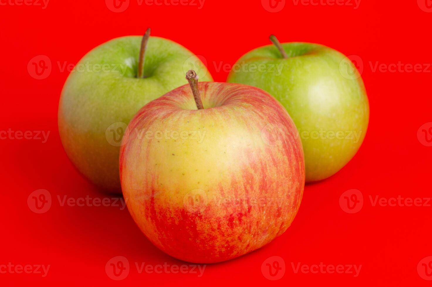 Three red apples and two green ones on a red background. photo