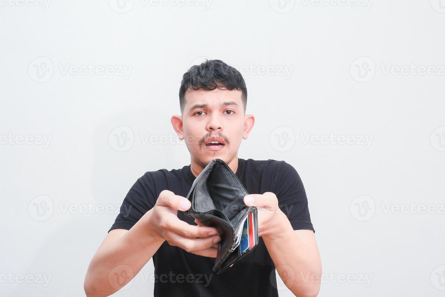 a portrait of asian young man holding his empty wallet with sad expression photo