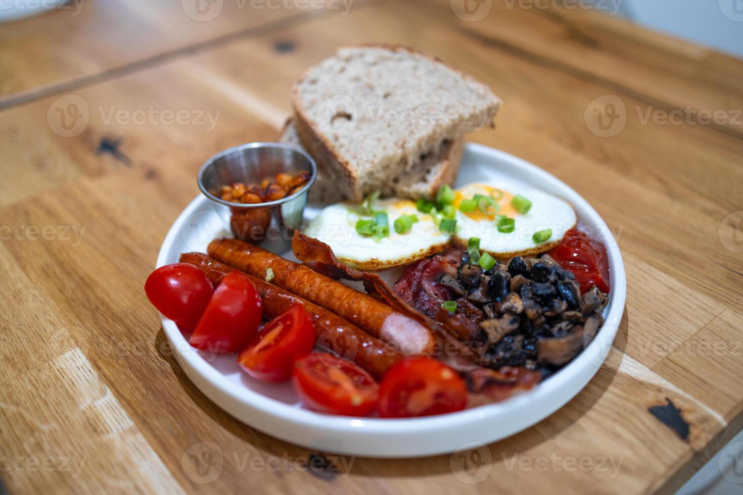 Breakfast with fried eggs, bacon and toasts on a white plate with cup of coffee on a stone background. Top view, selective focus photo