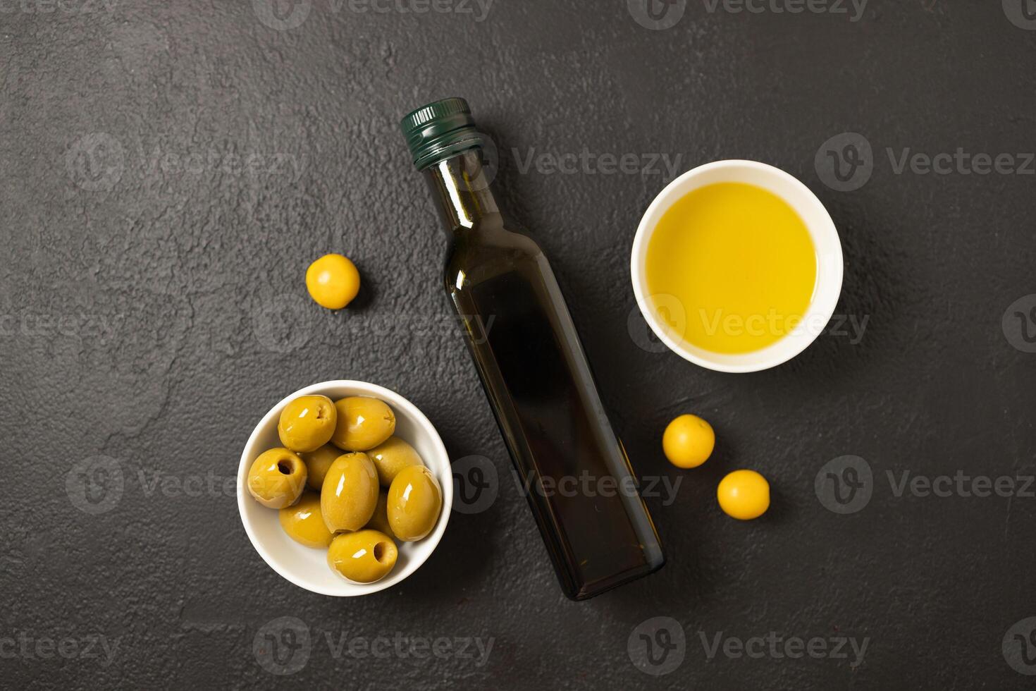 Olives and olive oil in bowl with bottle of olive oil on dark background. Mockup for package. Copy space. photo
