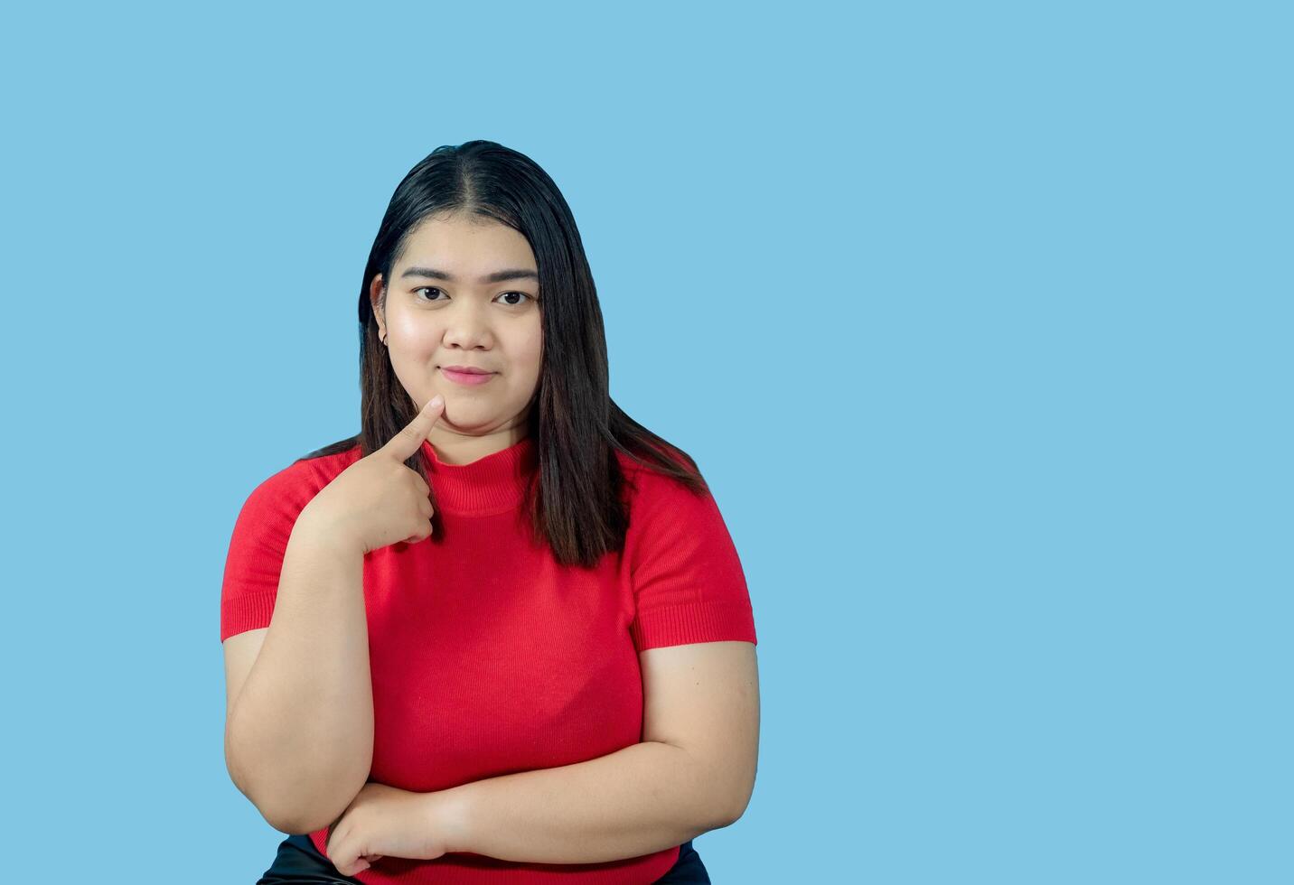 Portrait girl young woman asian chubby fat cute beautiful pretty one person wearing a red shirt is sitting, looking smiling happily holding copyspace imaginary on the isolated blue color background photo