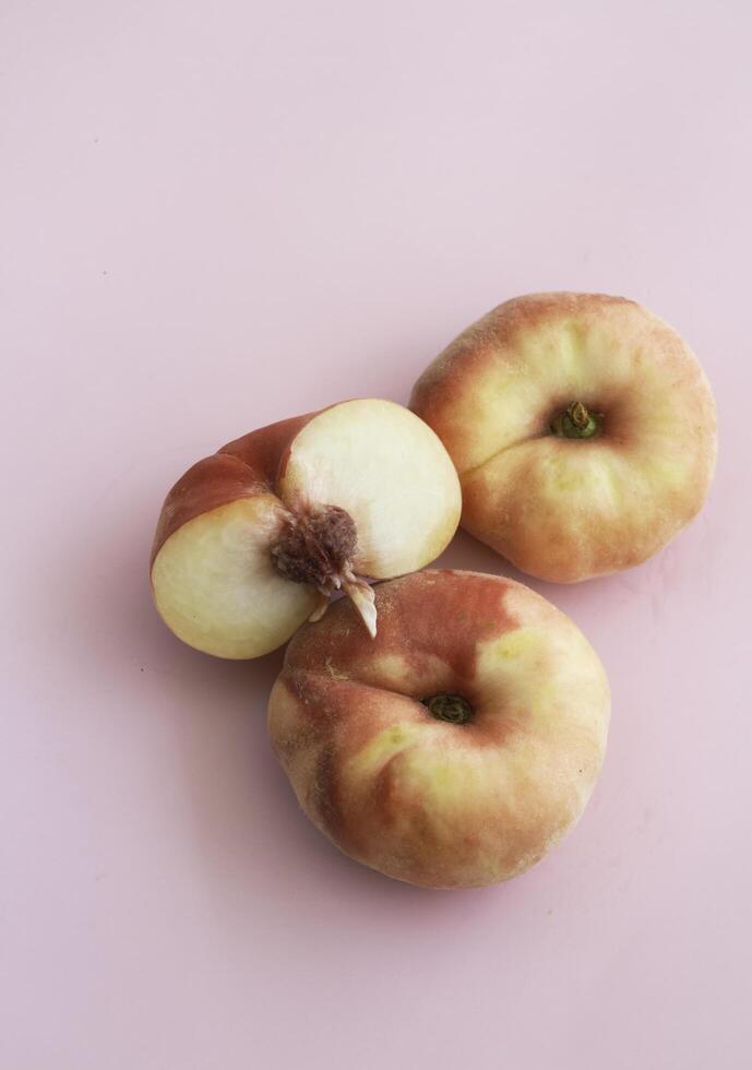 Doughnut Peach fruit with soft red orange peel put on pink background,b photo