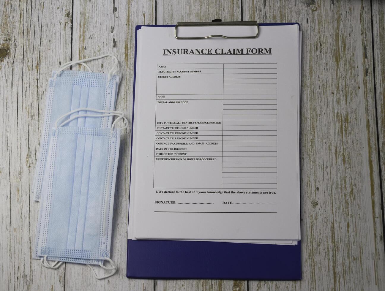 Surgical Mask and Insurance Claim Form put on wooden timber board photo