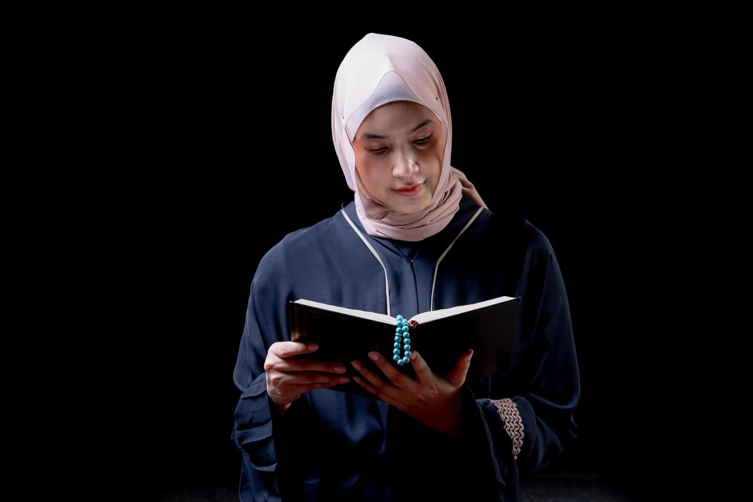 The image of an Asian Muslim woman in the Islamic religion in hijab in cream color. reading the Quran and having a happy smiling face Staying in a beautiful mosque out of respect for God. photo