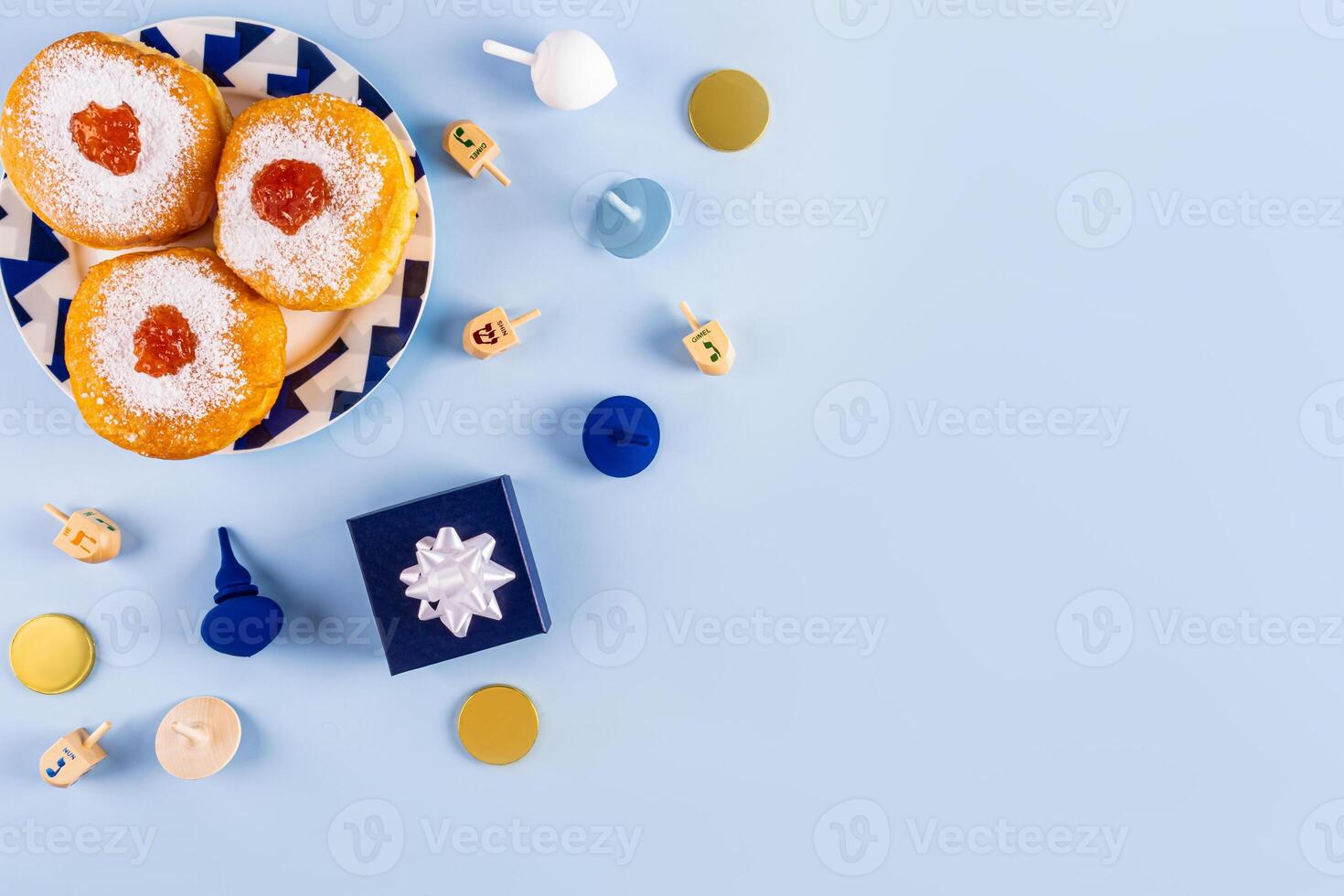 Traditional treats, symbols of the holiday of Hanukkah on a blue background. donuts, dreidels, chocolate coins for children. top view. A copy space. photo