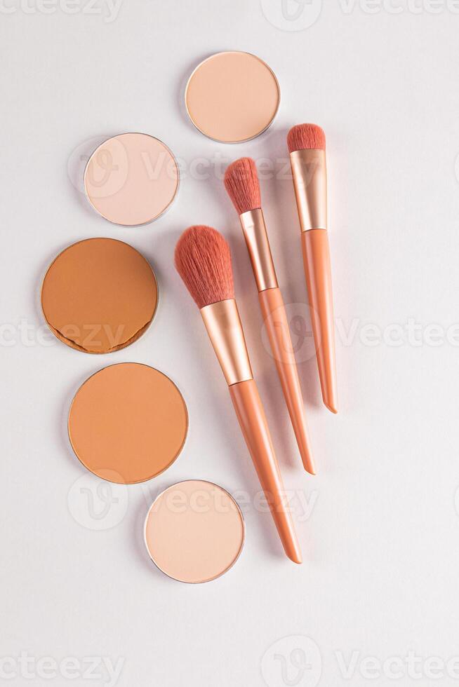 Beautiful beige makeup brushes and some round blocks, a refill of various tones on a white background. The top vertical view. flat lay. Decorative. photo