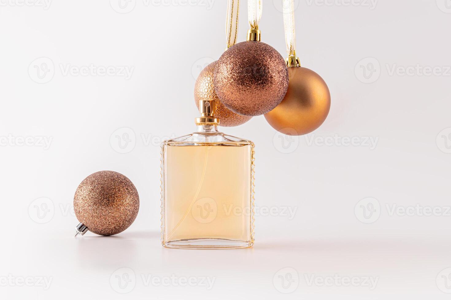 An elegant perfume bottle on a white background with New Year's chic brown balls hanging above it. Front view. A blank bottle mockup photo