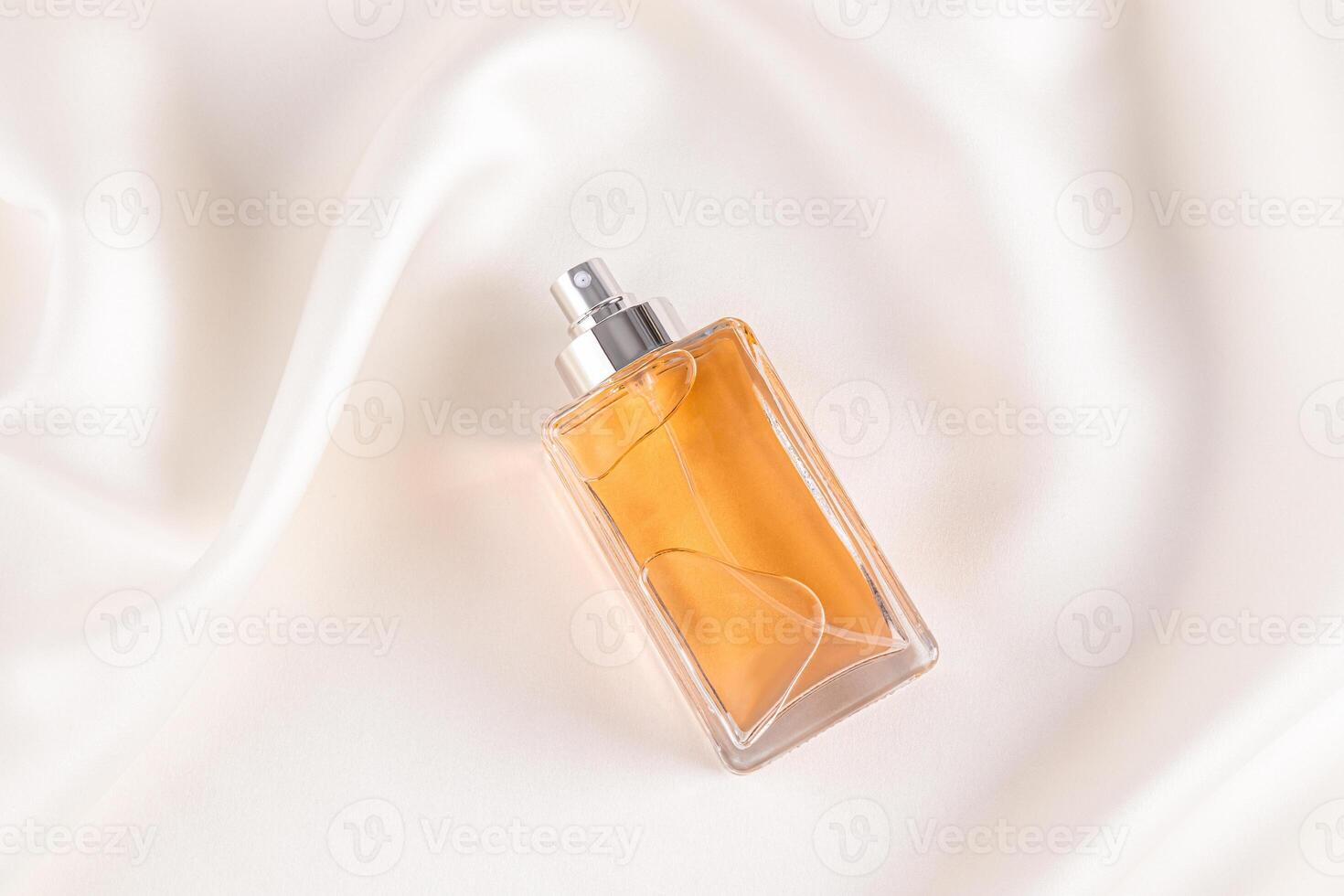 A chic unbranded bottle of perfume or cosmetic spray on a delicate beige satin among the soft waves of fabric. blank layout. Bottle. top view. photo