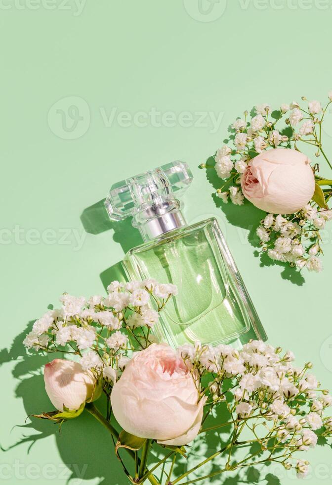An elegant bottle of women's perfume with a light floral fragrance on a green delicate background with flowers. The top vertical view. A copy space. . photo