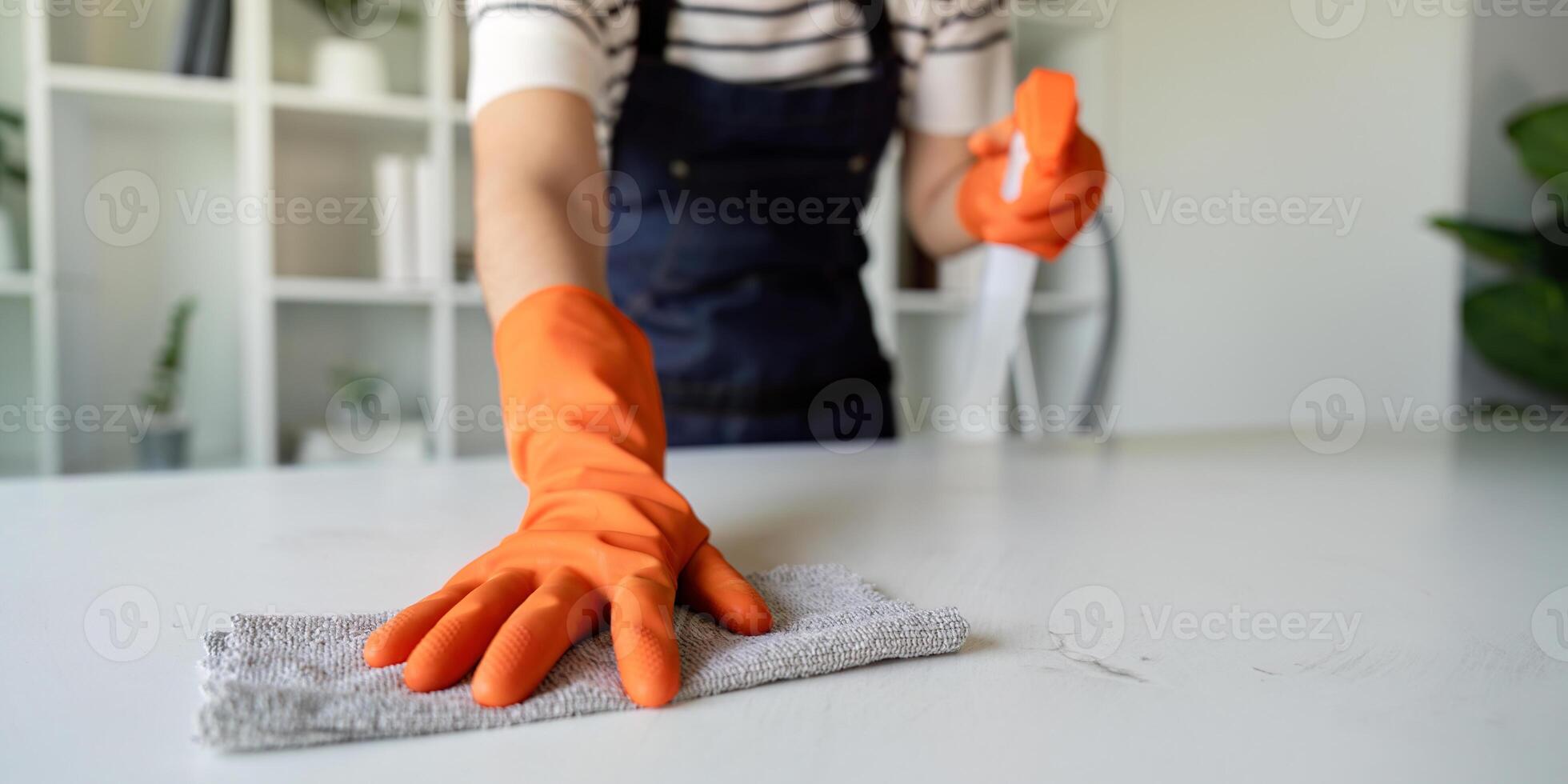 Person Cleaning Table with Cloth and Gloves in Bright Interior photo