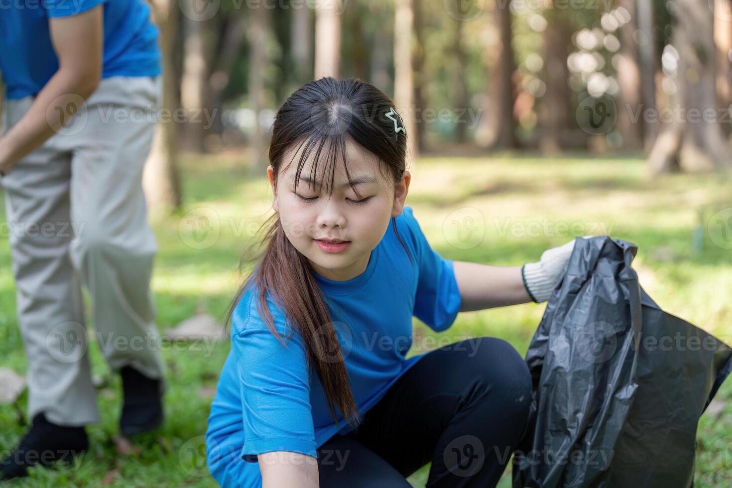 Young Asian girl volunteering in park collecting litter photo