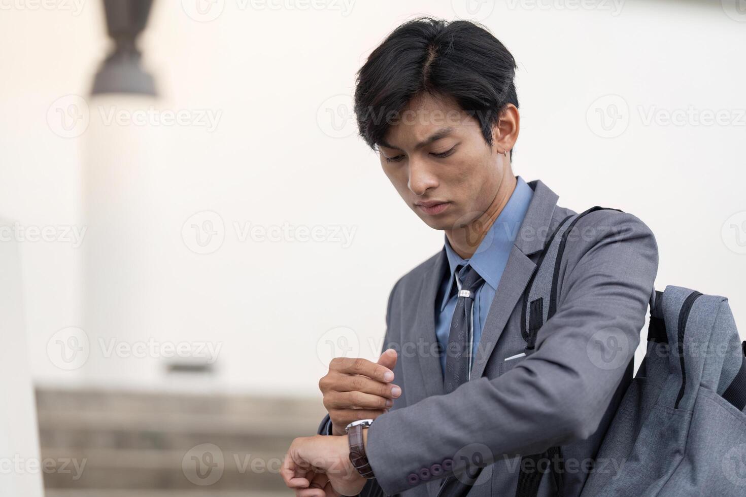 Young Asian businessman checking watch while on the move photo