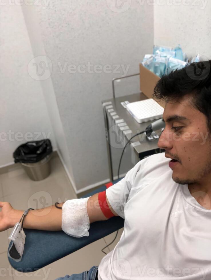 Young man donates blood while relaxing in a modern clinic setting photo