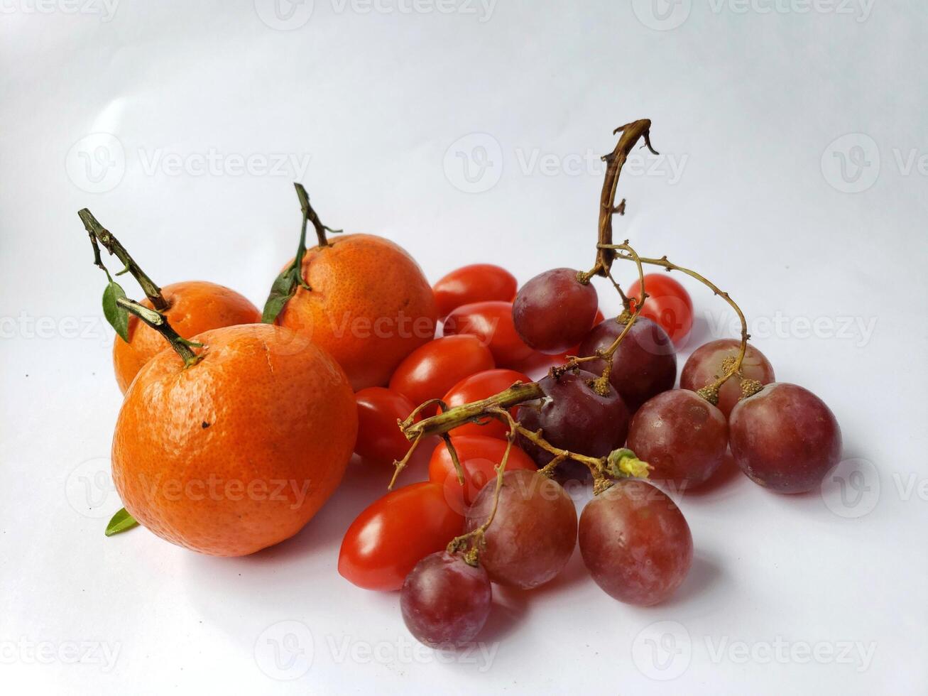 A bunch of grapes and oranges on a white surface photo