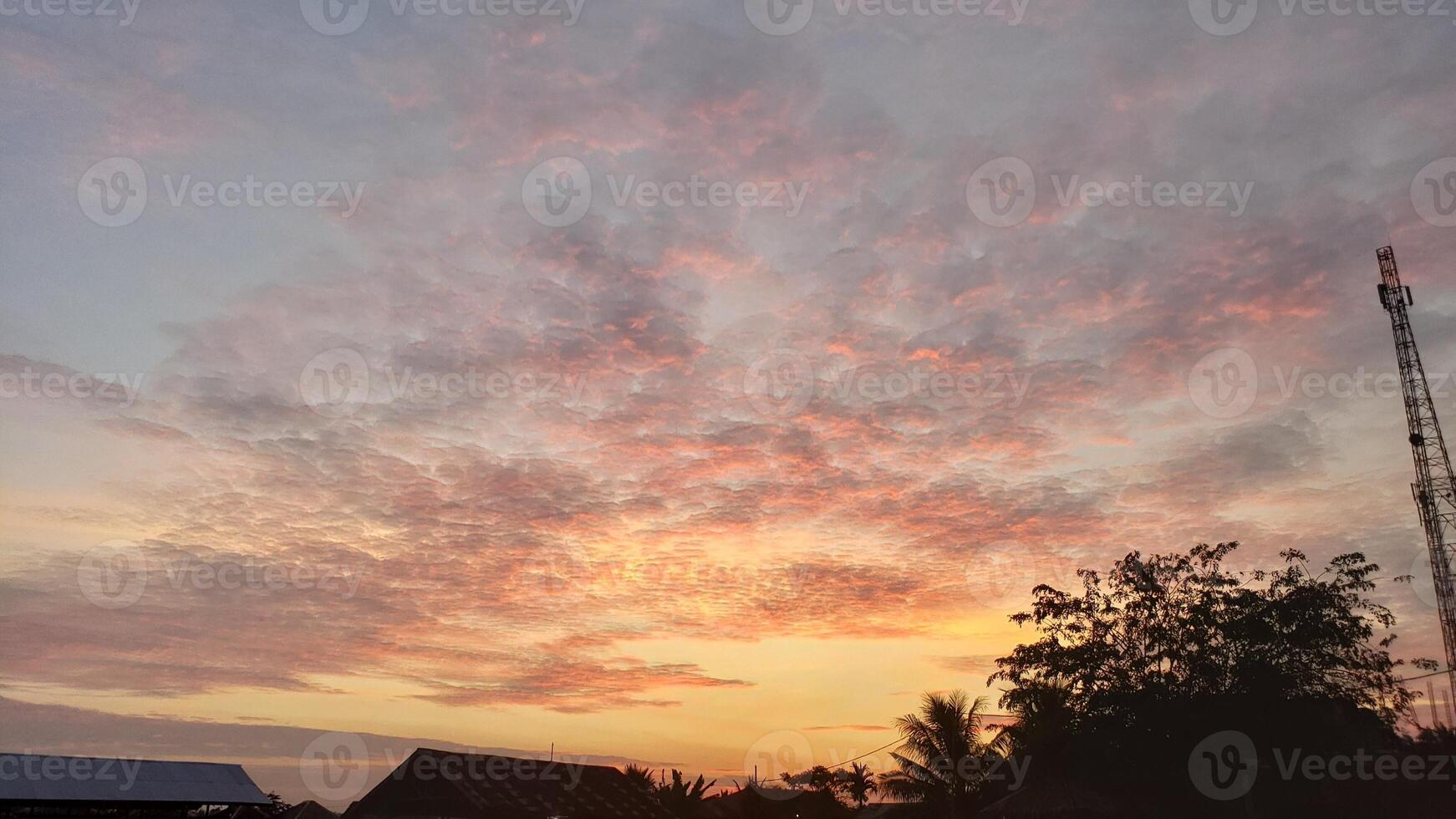 A sunset over a village with a tower in the background photo