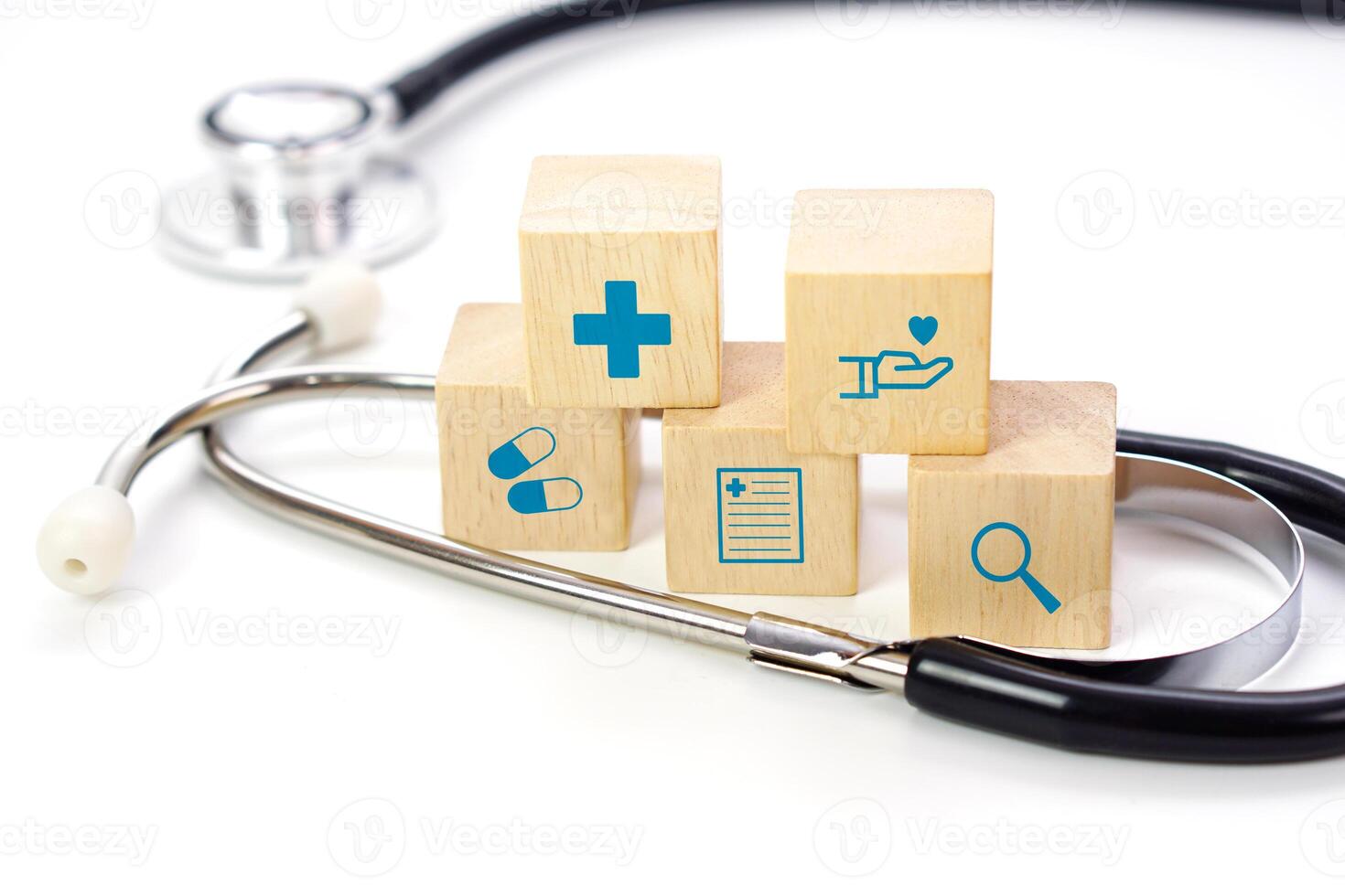 Focus on wooden block with medical icons symbol and blurred medical stethoscope. medical, treatment and health concept. photo