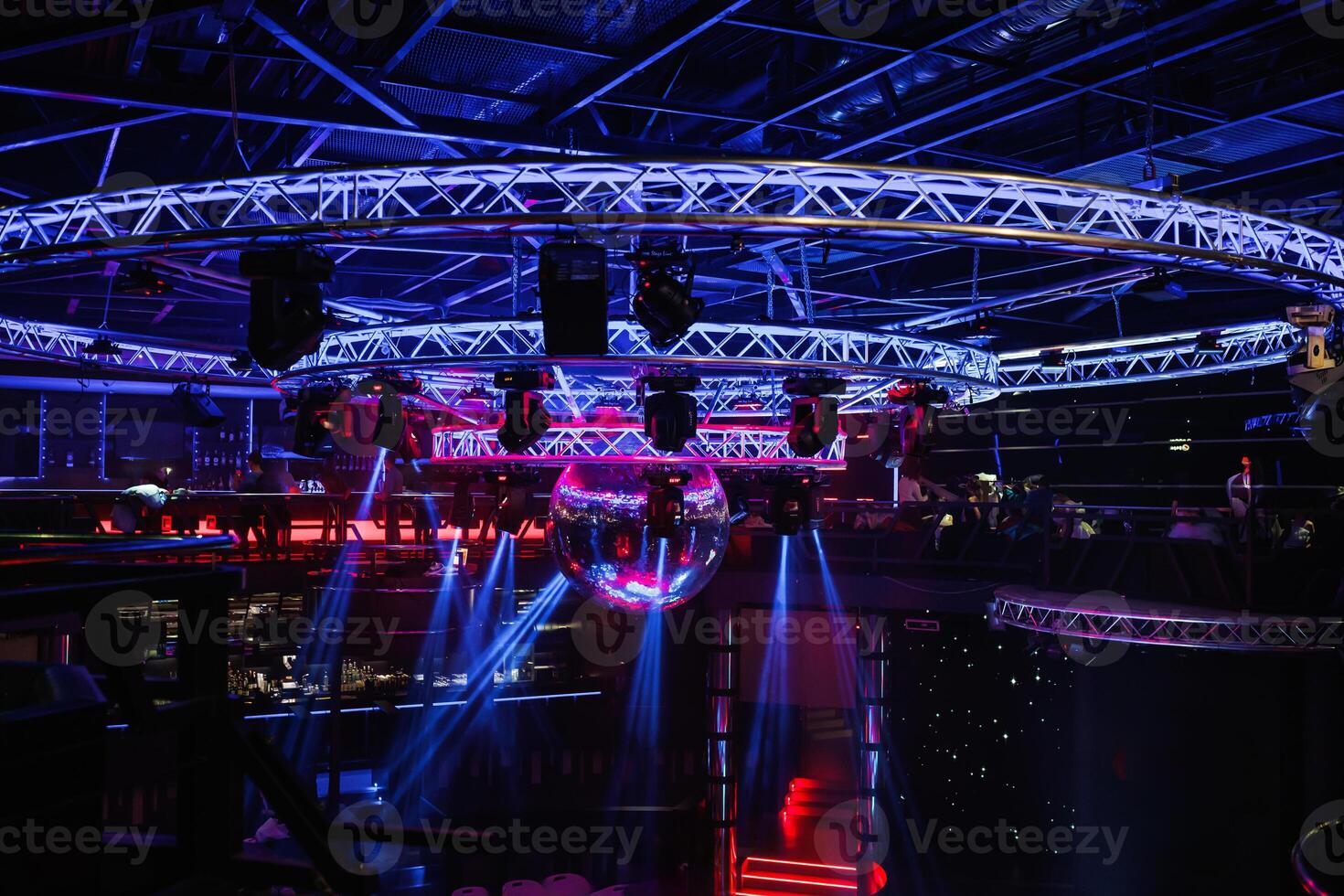 night disco club with neon blue violet red light, disco mirror ball and bright floodlight with round metal frame luminous construction photo