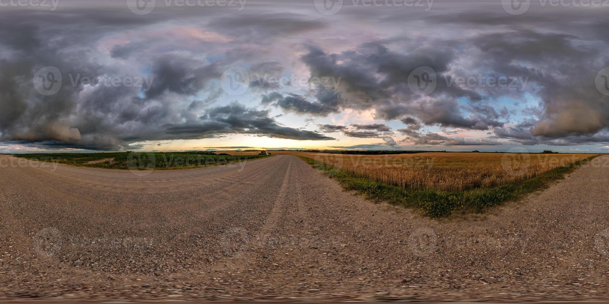 hdri 360 panorama on gravel road among fields in nasty evening before sunset with dark clouds in equirectangular full seamless spherical projection, for VR AR virtual reality content photo