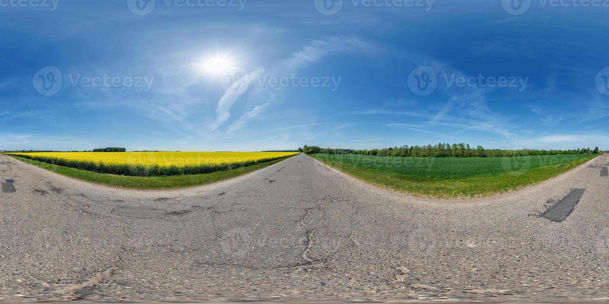 spherical 360 hdri panorama on old asphalt road with cracks near rapeseed canola colza fields with clouds on blue sky in equirectangular seamless projection photo