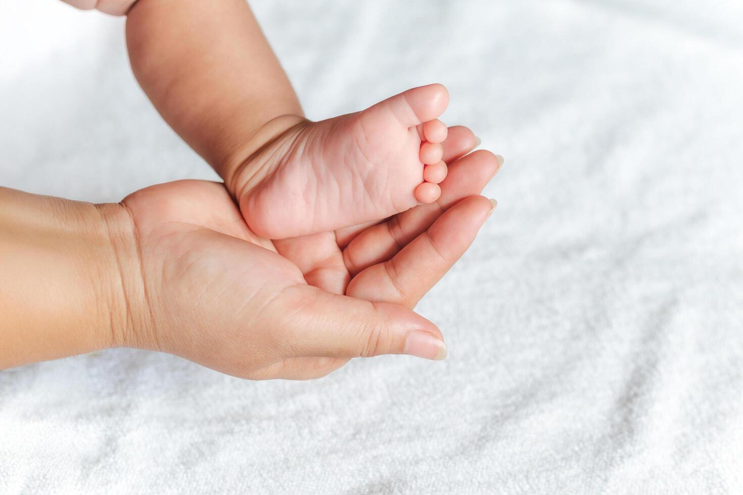 A baby's foot is held in a mother's hand. The baby is small and the mother is holding it gently. photo