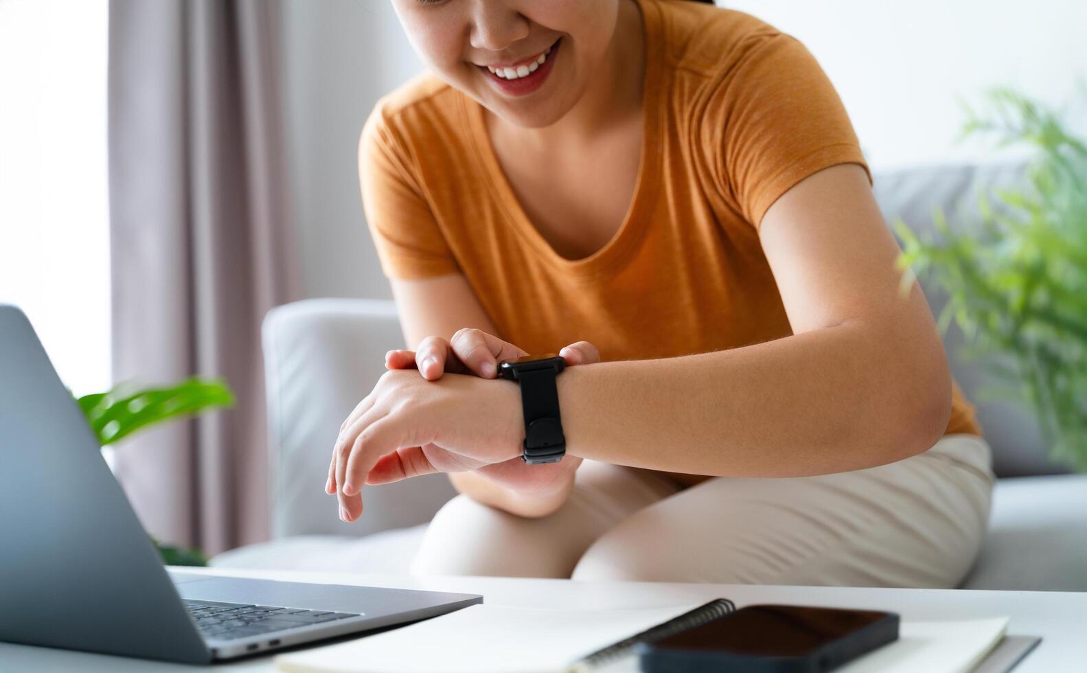 Happy young woman is using smartwatch on her wrist to check health data, notifications, set alarm. photo