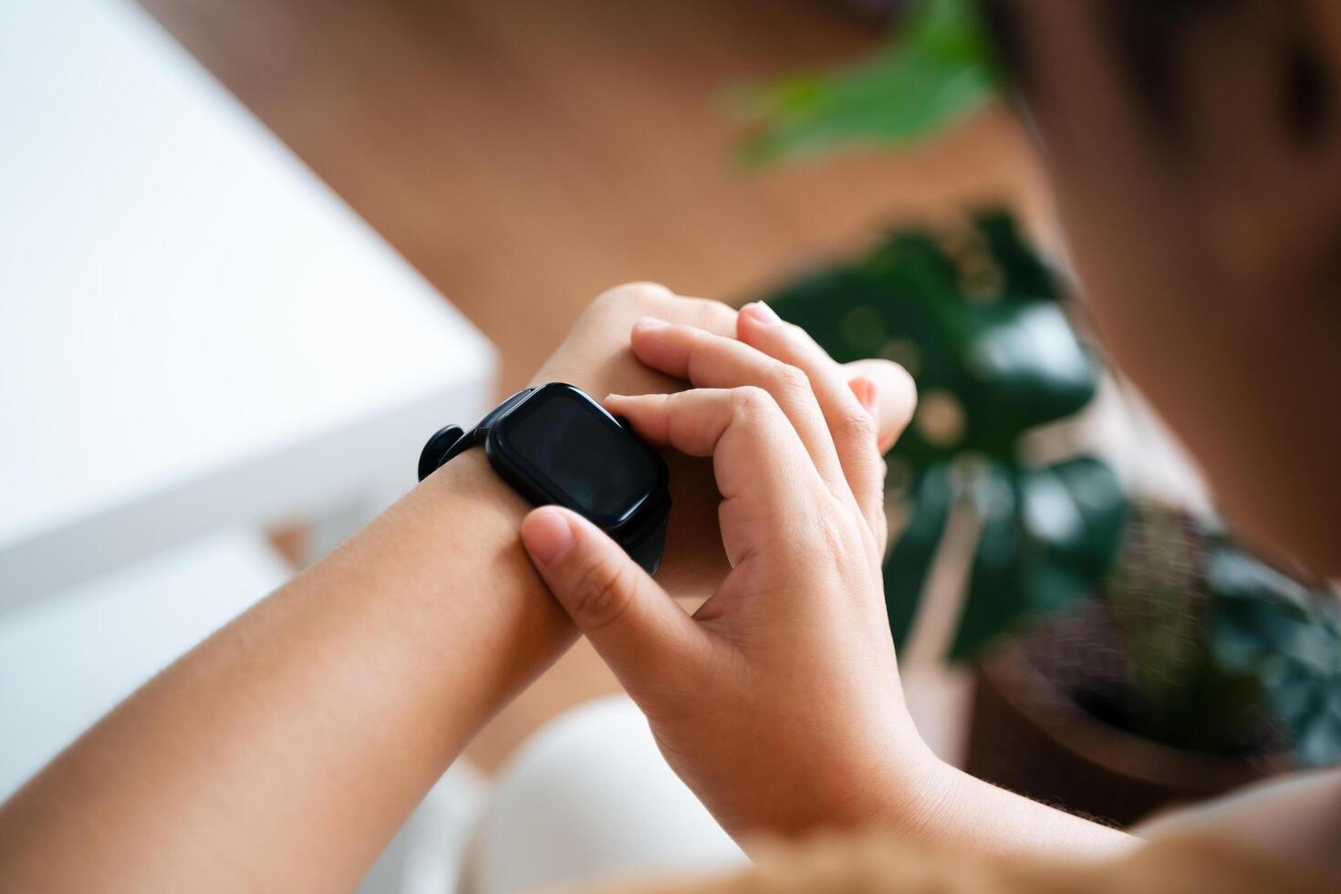 Happy young woman is using smartwatch on her wrist to check health data, notifications, set alarm. photo