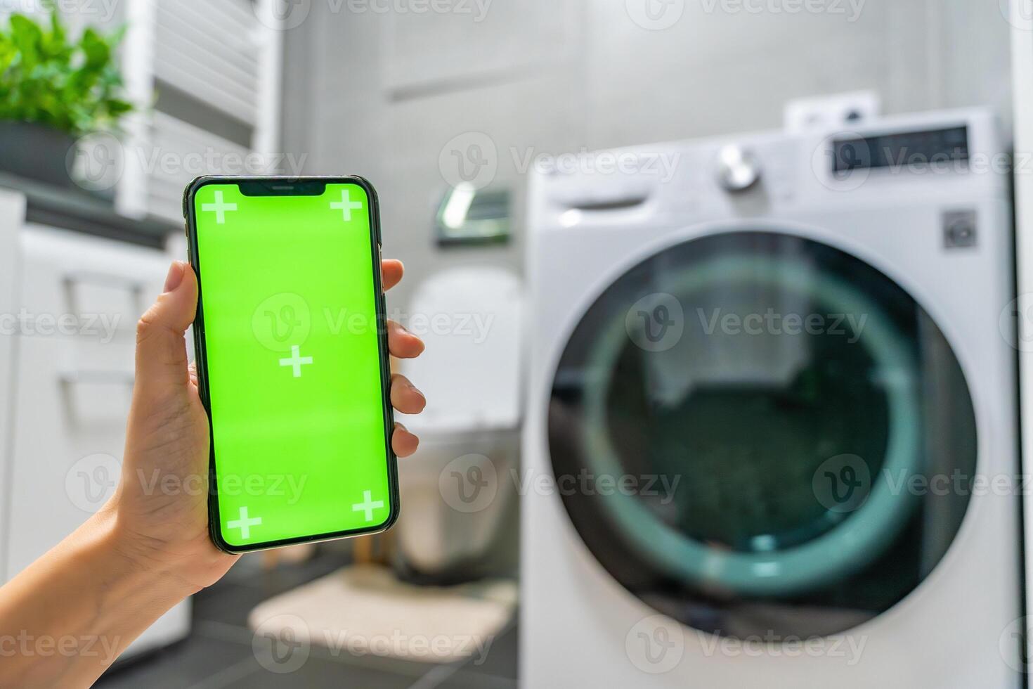 Young woman using mobile phone control via wi-fi and app for washing machine in home. Homesmart app, chroma key green screen. High quality photo