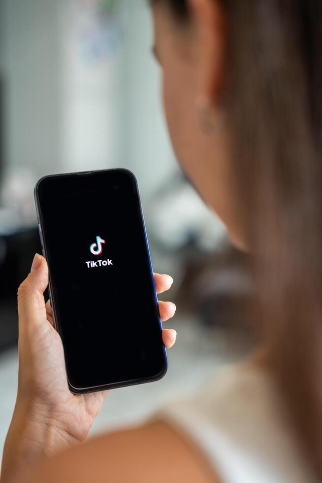 Prague, Czech republic - May 2, 2024. Woman holding iPhone with streaming service media and TikTok on the screen, using mobile application at home. High quality photo