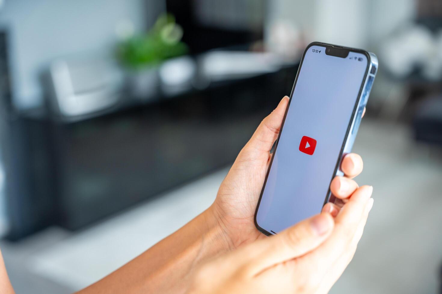 Prague, Czech republic - May 2, 2024. Woman holding iPhone with logo of application YouTube on the screen, using mobile application for business home. High quality photo