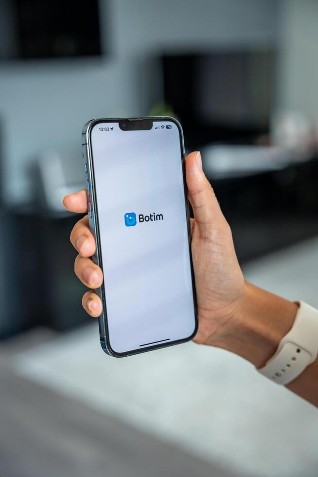 Prague, Czech republic - May 2, 2024. Woman holding iPhone with logo of application Botim on the screen, using mobile application for business home. High quality photo