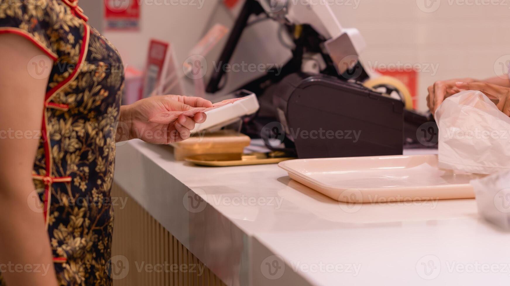 Woman in floral dress stands at vibrant checkout counter, thoughtfully holding card while preparing to finalize her order at bustling food outlet photo