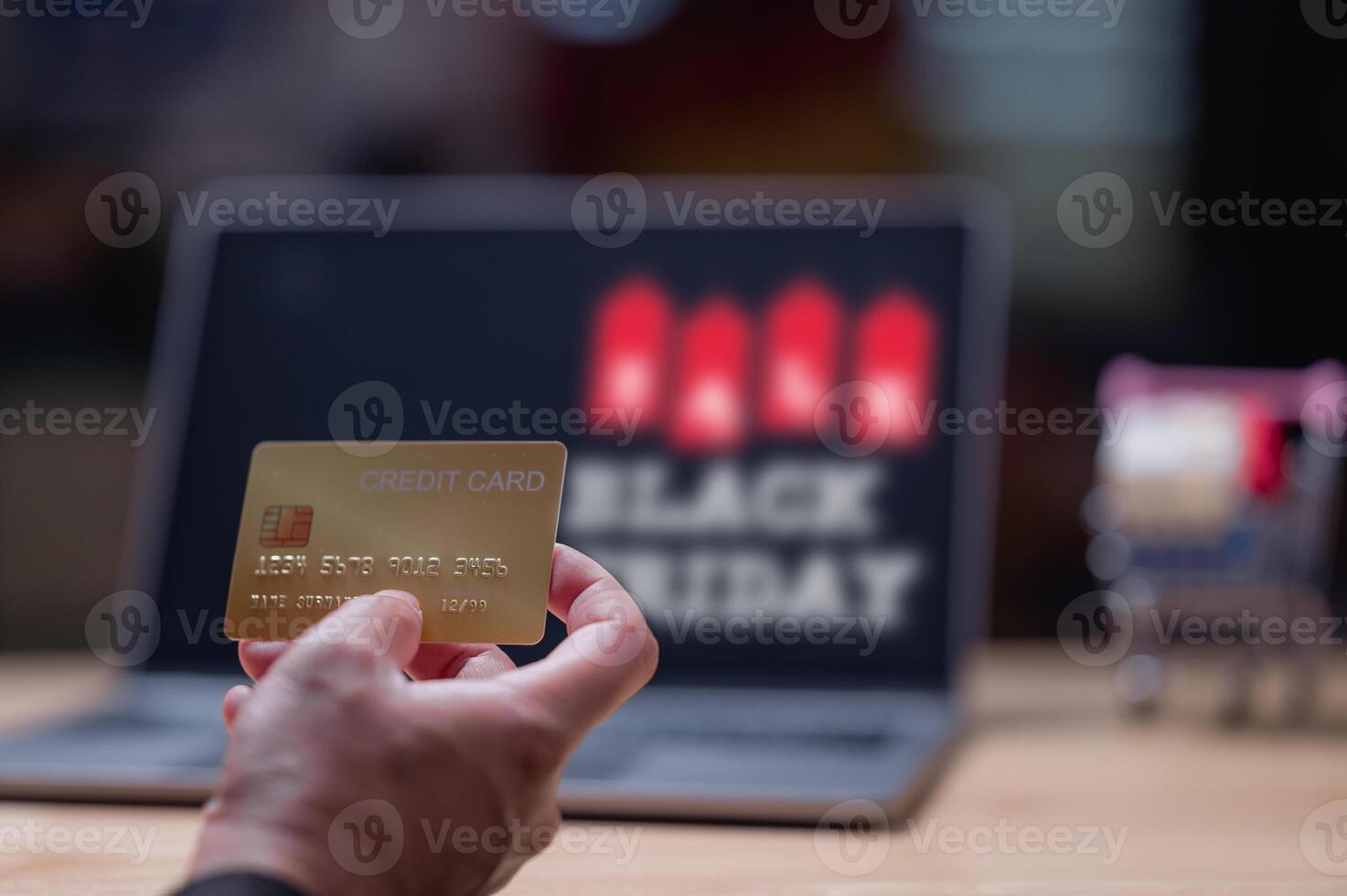 People shopping online using laptops concept. Person holds credit card in front of laptop displaying Black Friday sale image captures excitement of online shopping during holiday season photo