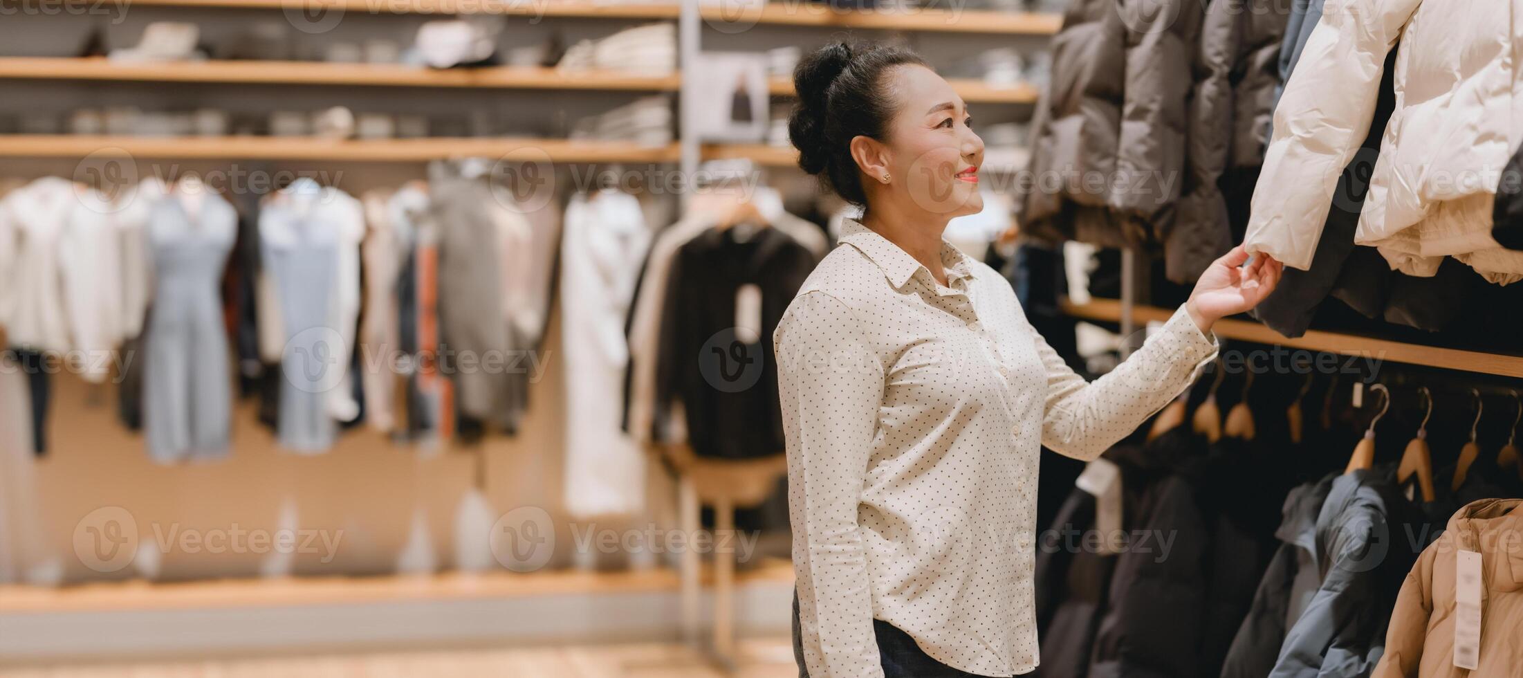 Woman smiles as she browses for jackets in stylish clothing store, indicating delightful shopping experience amidst variety of fashionable attire photo