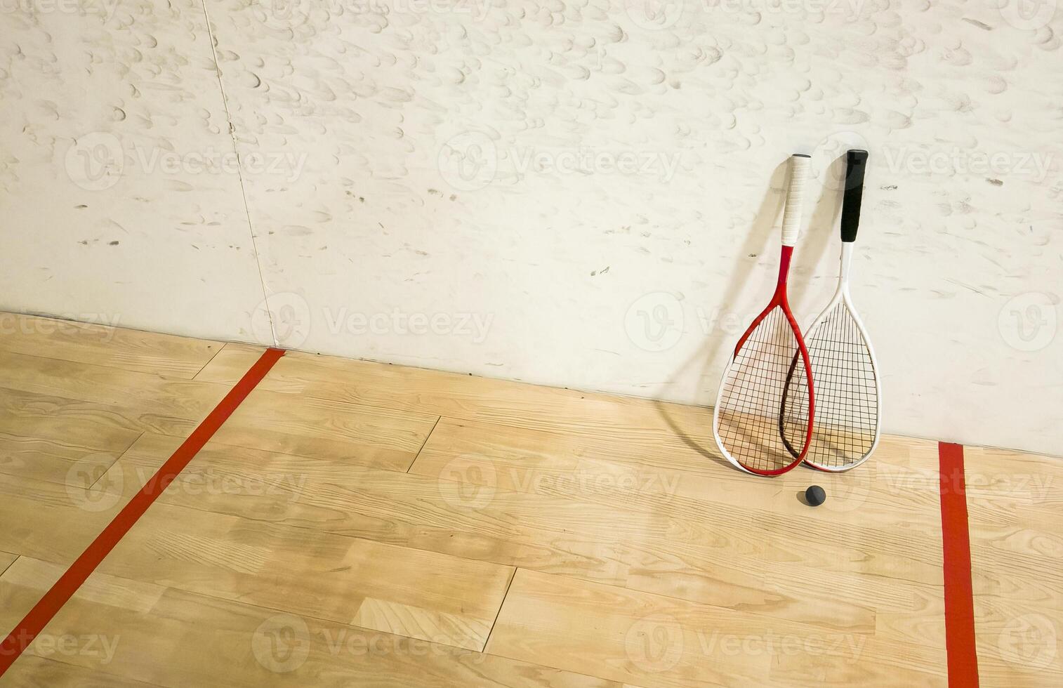 Two rackets and two squash balls lie on the parquet floor. photo