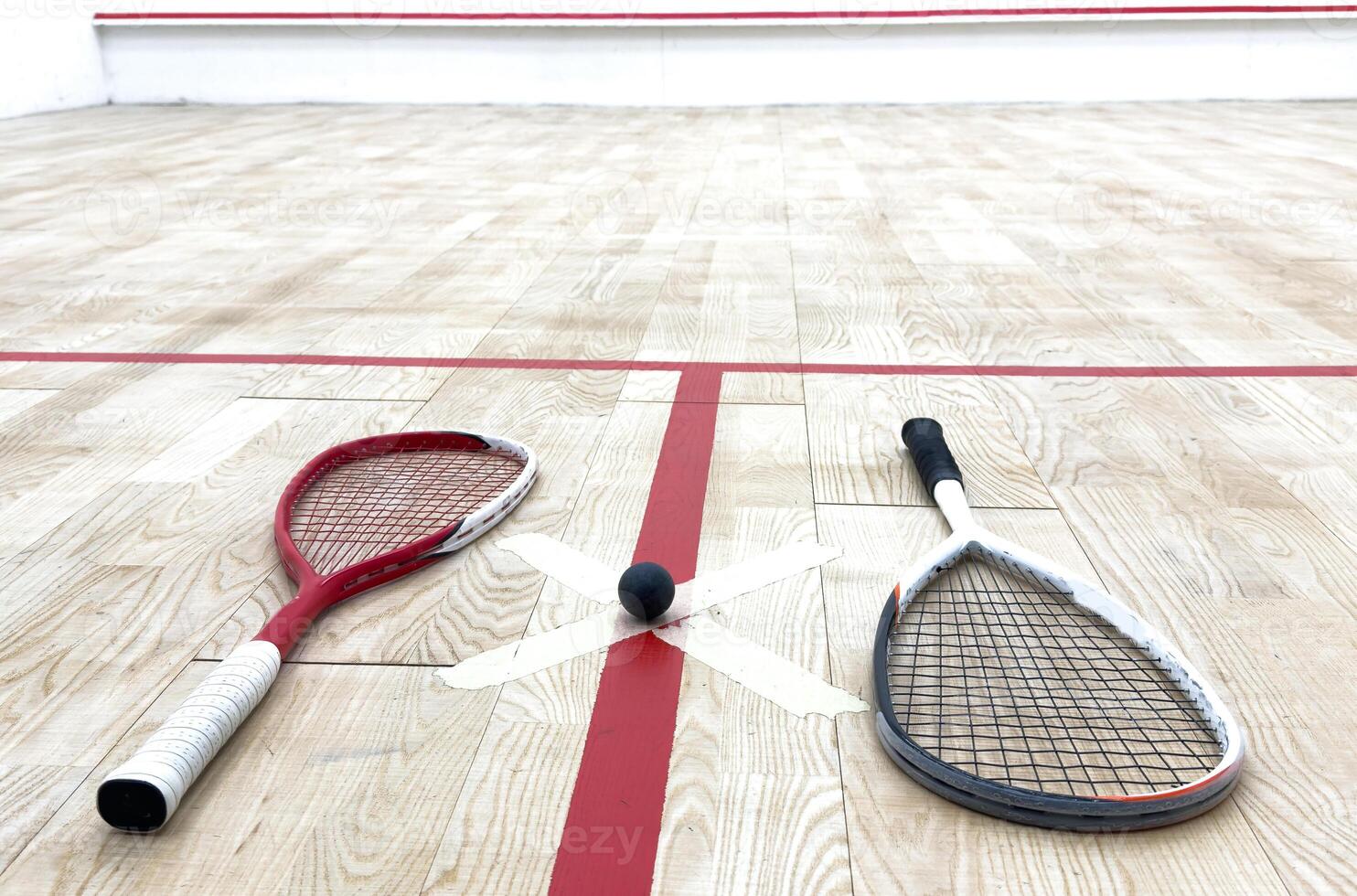 Two rackets and two squash balls lie on the parquet floor. photo