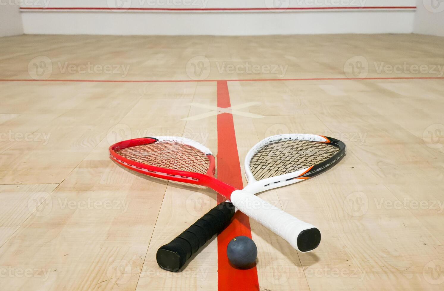 Two rackets and two squash balls lie on the parquet floor. photo