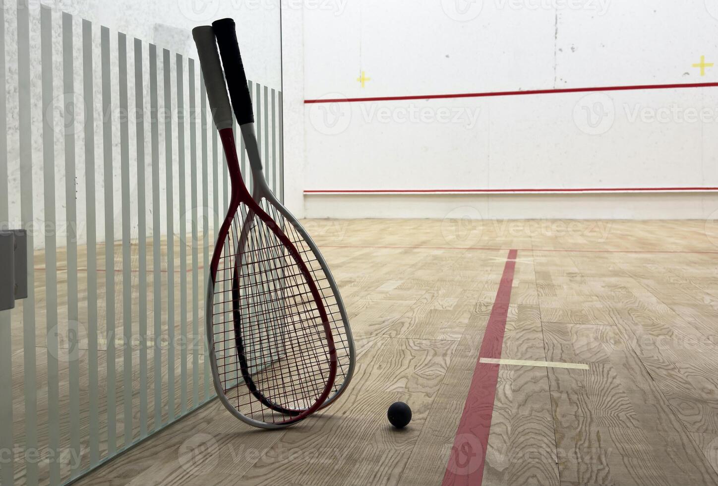 Two rackets and two squash balls lie on the parquet floor. photo