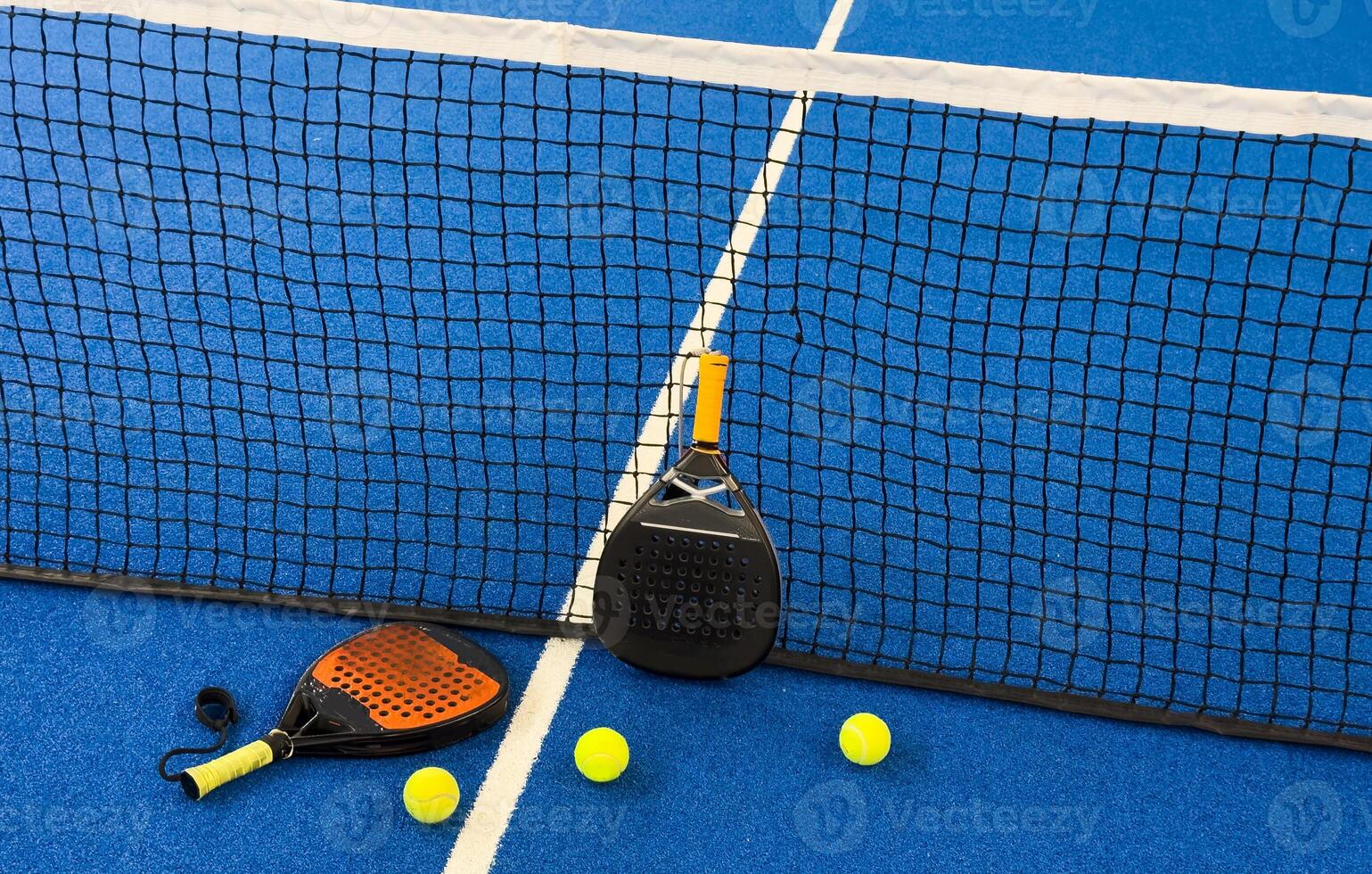 Black professional paddle tennis racket and ball with natural lighting on blue background. Horizontal sport theme poster, greeting cards, headers, website and app photo