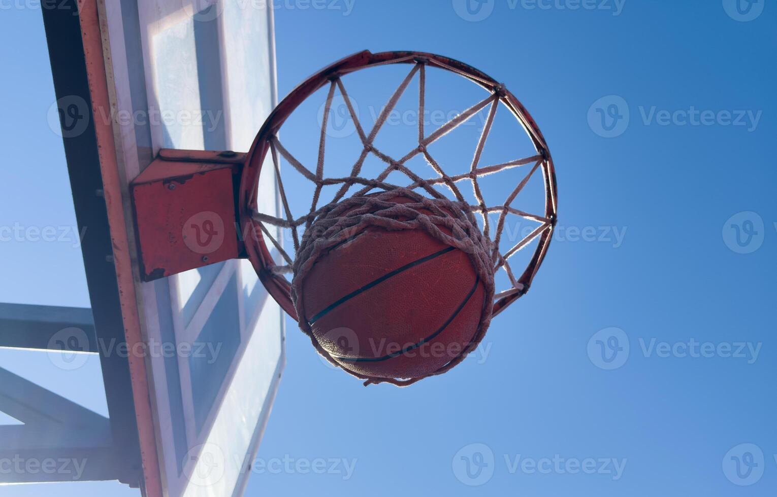 Basketball scoring a basket as it goes through the hoop and making a swish in the net photo